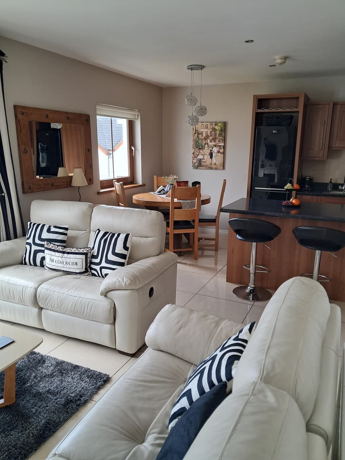 Bright apartment lounge with cream sofas, dining table and kitchen island
